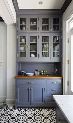 a kitchen with gray cabinets and black and white floor tiles