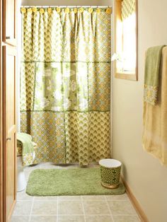 a bathroom with a green rug and yellow shower curtain in the window next to it