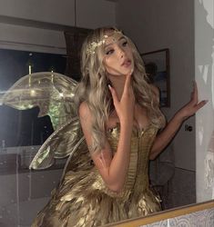 a woman dressed as a fairy standing in front of a mirror with her hand on her face