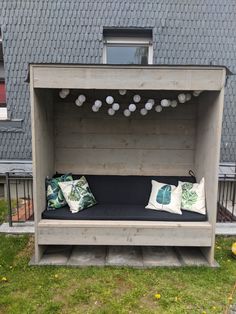 a bench made out of pallets with pillows on it in front of a house