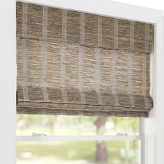 a window with a bamboo roman blind in front of the window and a tree outside