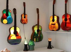 several guitars are hanging on the wall with stained glass windows behind them, along with other musical instruments