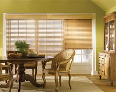 a dining room with green walls and wooden blinds on the windowsills is shown