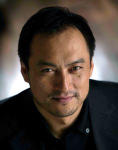 a close up of a person wearing a black shirt and looking at the camera with a serious look on his face