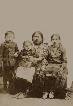 an old black and white photo of three people with two small children on their lap