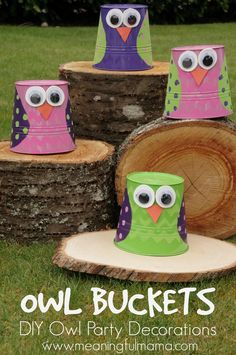 paper owl buckets are sitting on top of wood logs in the grass with eyes painted on them