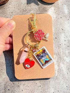 a hand holding a keychain with two charms on it and a card attached to it