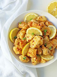 a white bowl filled with chicken and lemons