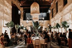 people sitting at tables in a large room with chandeliers hanging from the ceiling