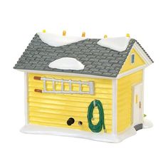 a yellow toy house with snow on the roof and green wreath hanging from it's chimney