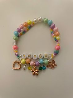 a bracelet with beads and charms that say yntuco on the clasps