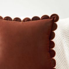 a brown pillow with scalloped edges sitting on a white bedding and pillows