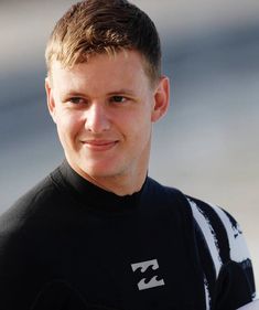 a young man in a black shirt holding a white surfboard