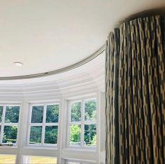 a living room with large windows and curtains on the window sill, looking out onto an open field