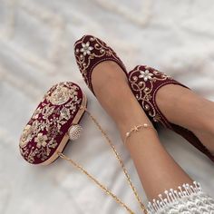 a woman's feet wearing red velvet slippers and beaded shoes