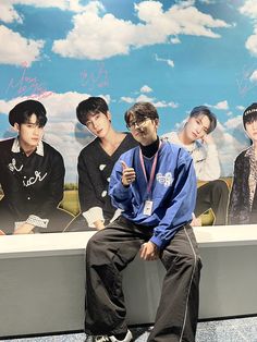 a man sitting on top of a bench in front of a poster