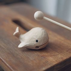 a small wooden toy whale sitting on top of a wooden table next to chopsticks