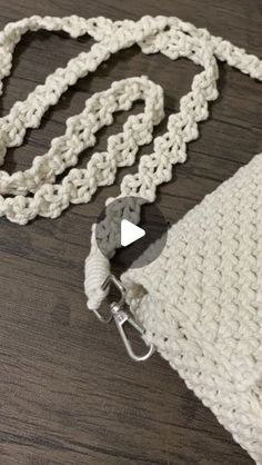 a white crocheted bag sitting on top of a wooden floor next to a pair of scissors