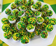 cupcakes with green and yellow decorations are arranged on a white platter, ready to be eaten