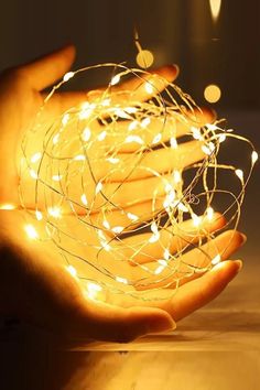 a person holding out their hand with some lights in the shape of a ball on it