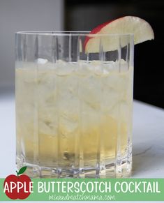 an apple is sitting on the table next to a glass with ice and a red apple