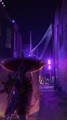 a street at night with purple lights and an umbrella on the top of a trash can