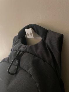 a black backpack hanging on the wall with a white tag attached to it's side