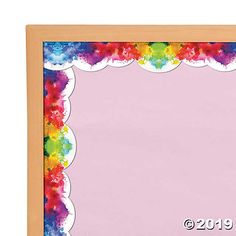 a wooden frame with colorful paint splattered on the edges and an empty pink background