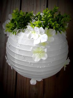 a white vase filled with flowers on top of a wooden table