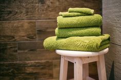 a stack of green towels sitting on top of a stool