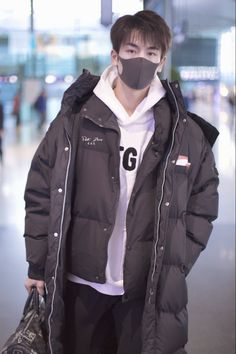 a man with a mask on his face is holding a bag and wearing a jacket