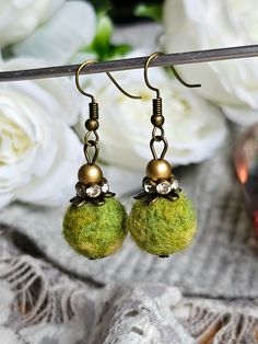 two green balls are hanging from the hooks of some kind of earring set