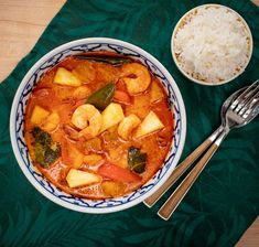 a bowl filled with food next to a spoon and rice on top of a green table cloth