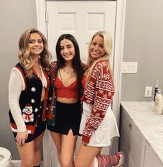 three beautiful women standing next to each other in a bathroom