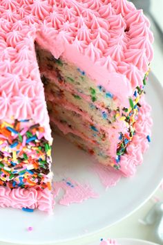 a cake with pink frosting and sprinkles is cut from the plate