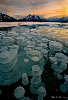 the water is crystal clear and has many bubbles on it, with mountains in the background