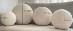 three white eggs sitting on top of a couch next to each other with measurements for them