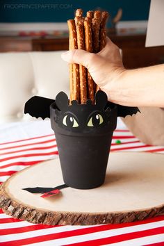 a person is holding crackers in front of a black cup with bats on it