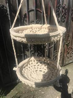 two baskets are hanging from the side of a gate, and one is made out of rope