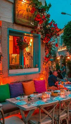 an outdoor dining area with tables, chairs and potted plants on the outside wall