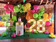 balloons and streamers decorate the entrance to a tropical themed birthday party with neon colors