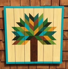 a wooden wall hanging with a tree painted on it's side and wood planks in the background