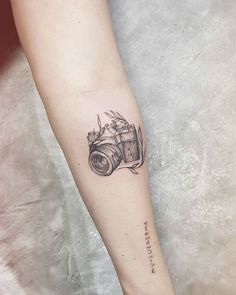 a camera tattoo on the left inner arm