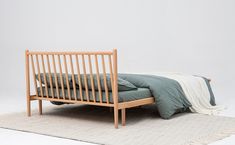 a bed sitting on top of a white rug next to a wooden frame and headboard