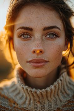 a woman with freckled hair and blue eyes looks into the camera while wearing a sweater