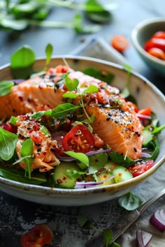 a bowl filled with salmon and vegetables on top of a table