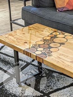 a wooden table sitting on top of a rug in front of a gray couch and black chair