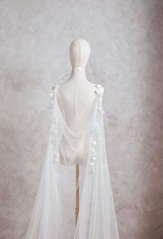 a mannequin wearing a white wedding veil with flowers on the top and bottom