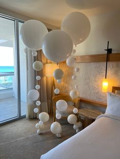 white balloons floating from the ceiling in a hotel room next to a bed with pillows on it