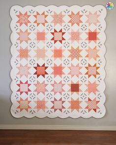 an orange and white quilt hanging on the wall